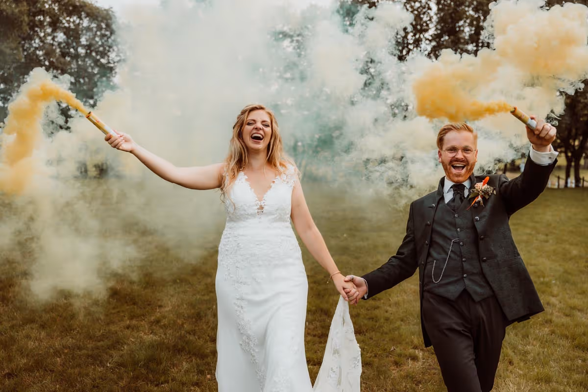bruid en bruidegom hand in hand en beide hebben een gele rookfakkel vast