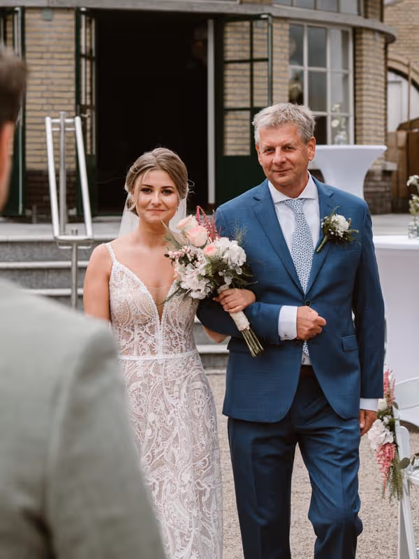 bruid arm in arm met vader, lopend naar bruidegom bij de ceremonie