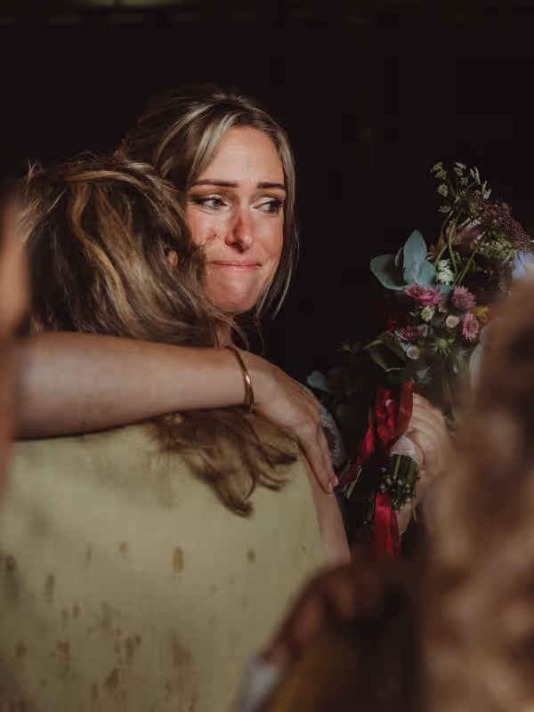 Bruid met tranen die gast een knuffel geeft