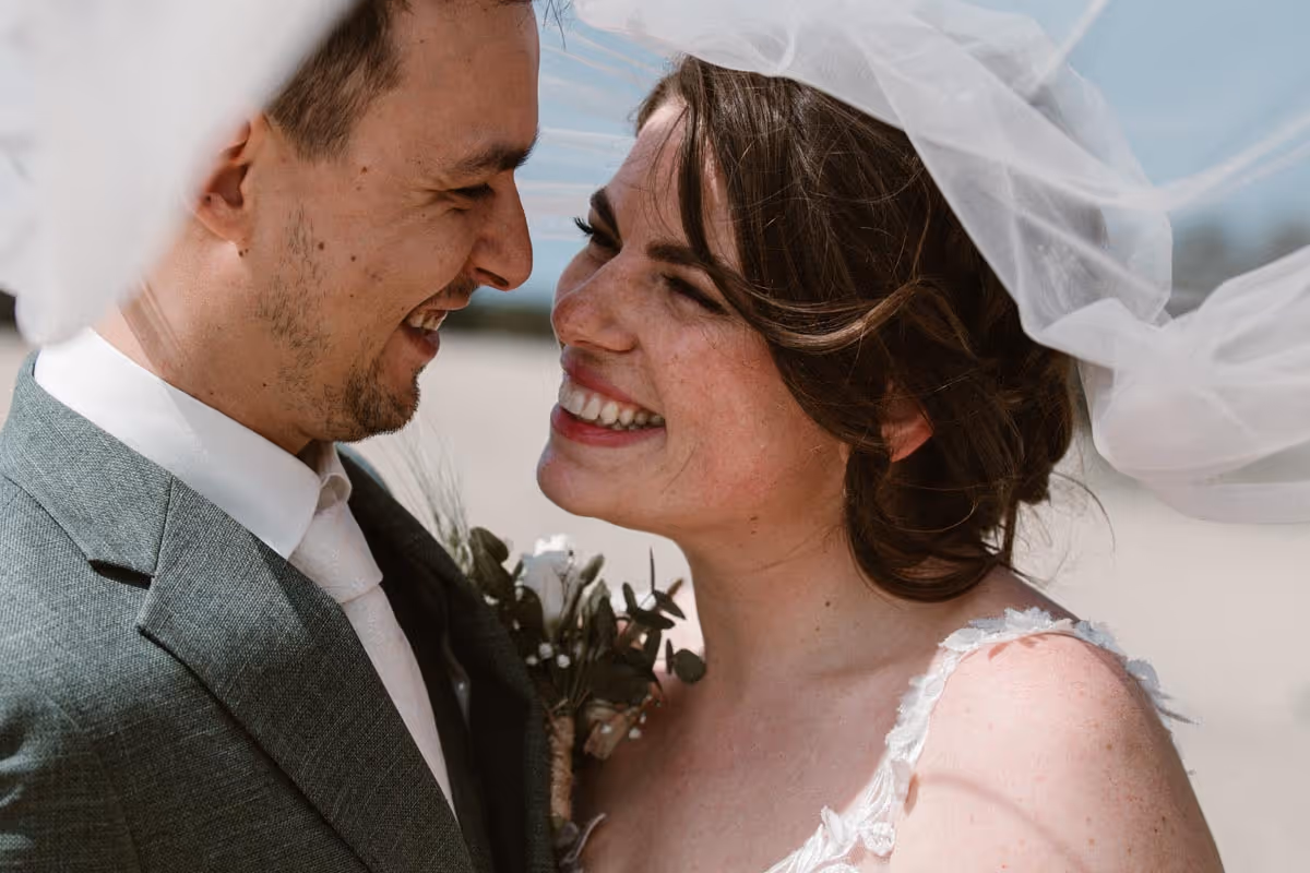 close up van bruidspaar onder een wapperende sluier