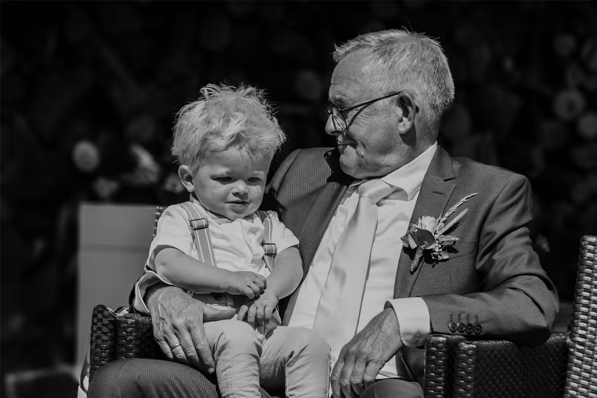 Opa met kleinzoon, bruidsjongen op schoot in zwart wit