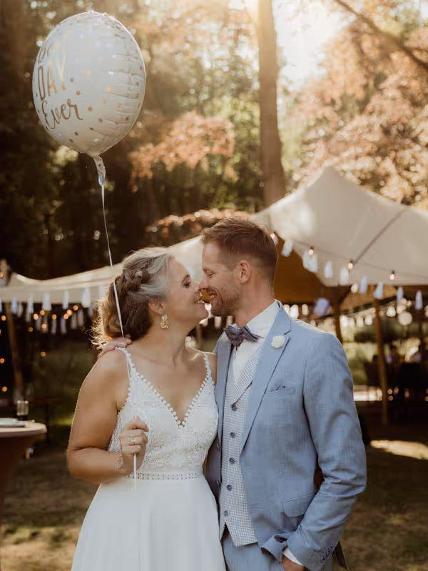 Bruidspaar wat elkaar aankijkt met ballon in de hand met de tekst best day ever