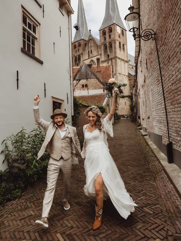 Bruidspaar loprnd door deventer stad met handen in de lucht